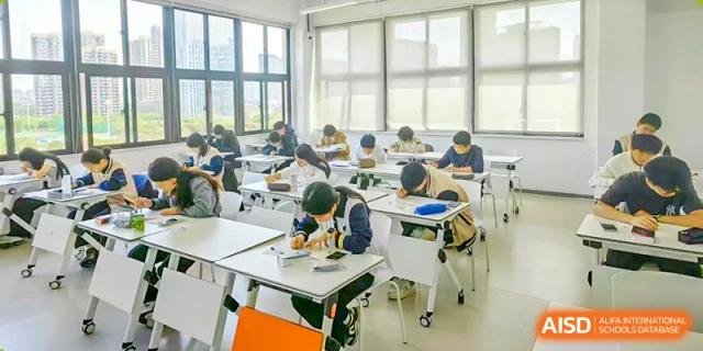 A wide shot of students at Maple Glory Education focused on individual work at desks in a bright, modern classroom.