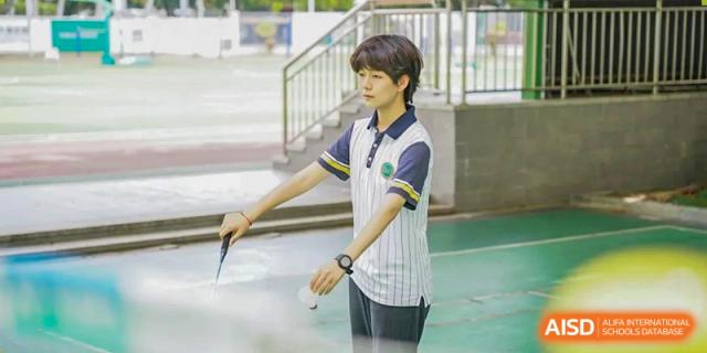 A student from Maple Glory Education wearing a polo shirt and watch standing on an outdoor court.