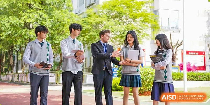 Two students from Maple Glory Education in uniform speaking with a male instructor in a suit outdoors.