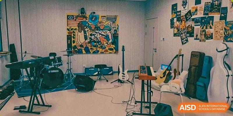 An indoor music practice room at Maple Glory Education with musical instruments, a drum set, and a large poster on the wall.