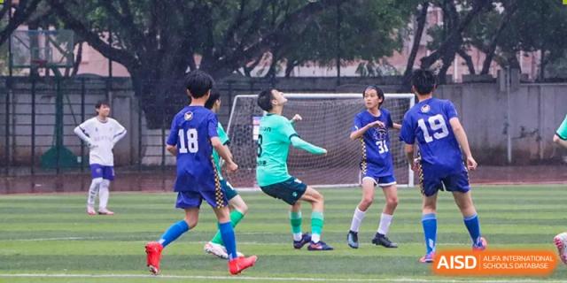 An action shot of Maple Glory Education students playing football (soccer) on an outdoor turf field.