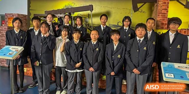 A group of male and female high school students in black uniforms posing together indoors at Maple Leaf International School Wuhan.
