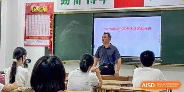A teacher speaking to students in a classroom, with the topic of the lesson displayed on the screen behind him, at Maple Leaf International School Wuhan.