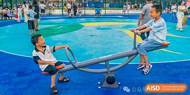 A close-up view of a playground with a seesaw and colorful blue and green safety surface at Maple Leaf International School Wuhan.