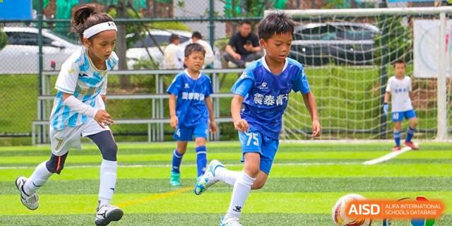 A boy in a blue soccer uniform running with the ball on the green turf field during a soccer game at Maple Leaf International School Wuhan.