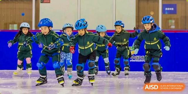 Young students in full blue and yellow protective gear skating on an ice rink or roller rink at Maple Leaf International School Wuhan.