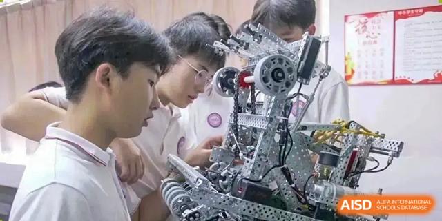 Male students working collaboratively on a complex robotics or engineering project in a classroom at Oxstand International School, Shenzhen.