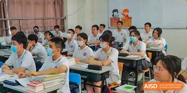 A classroom full of students, many wearing masks, sitting at their desks during a lesson at Oxstand International School, Shenzhen.