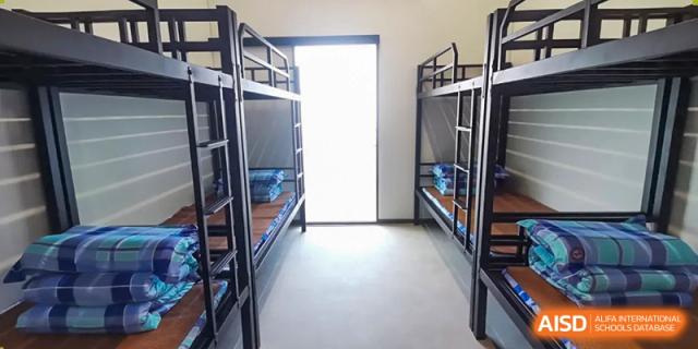 A minimalist dormitory room furnished with two sets of black metal bunk beds at Oxstand International School, Shenzhen.