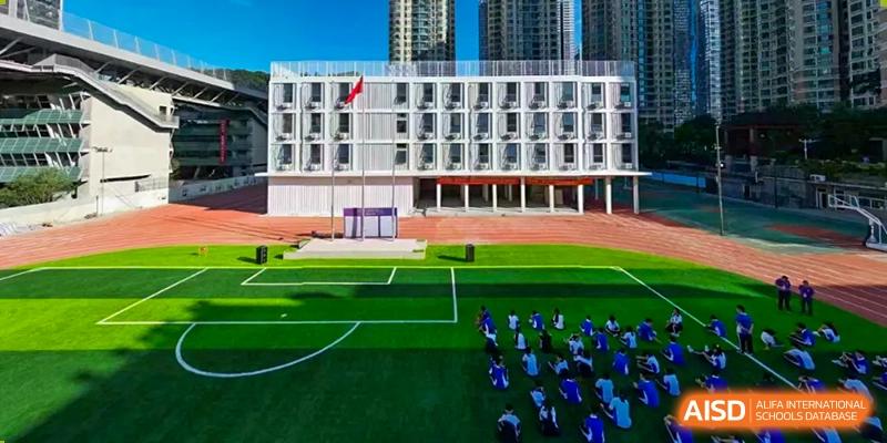 An aerial view of the modern school building and a large green sports field where students are gathered at Oxstand International School, Shenzhen.