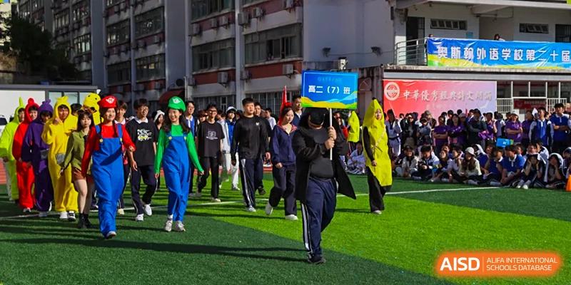 Students walking across the sports field during an event, with one student in bright green overalls, at Oxstand International School, Shenzhen.