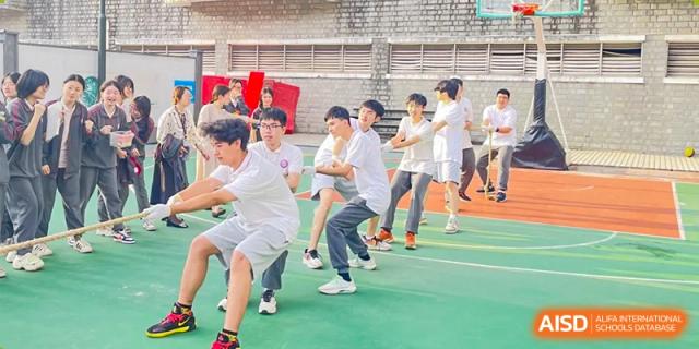A group of male students participating in a tug-of-war competition on a grassy field at Oxstand International School, Shenzhen.