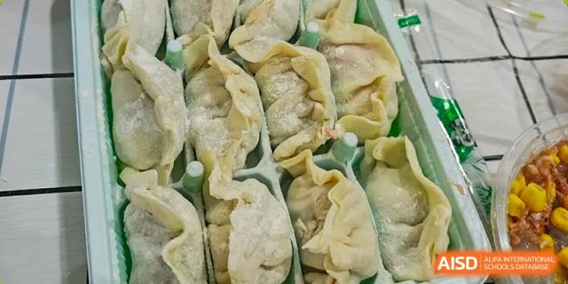 A close-up view of freshly made, uncooked dumplings (jiaozi) neatly arranged in a preparation tray at Oxstand International School, Shenzhen.