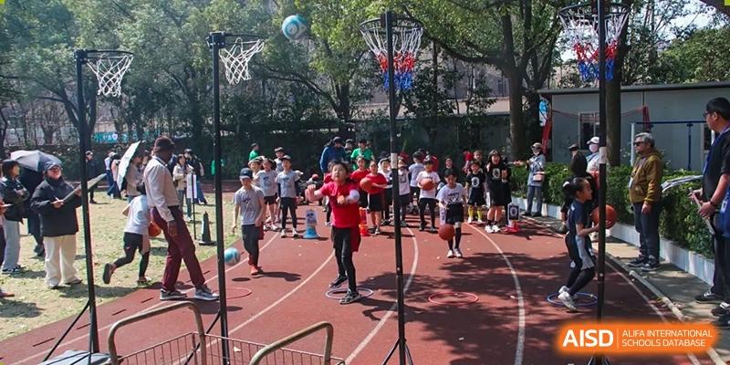 Shanghai Livingston American School students playing basketball outdoors on a court with spectators.