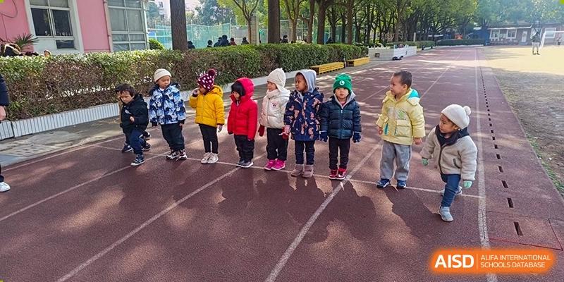 Young Shanghai Livingston American School students standing in a line on a running track for an activity or race.
