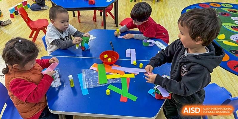 Shanghai Livingston American School students engaged in a hands-on learning activity with colored blocks and balls on a blue table.