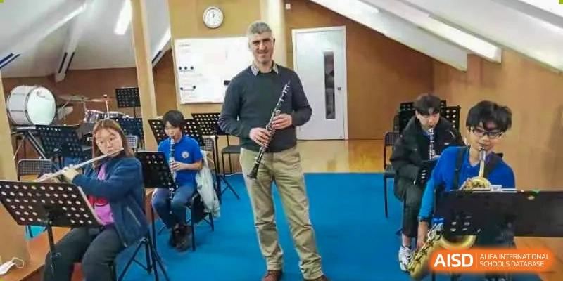 A Shanghai Livingston American School teacher or guest performing on a clarinet during an indoor event or concert.