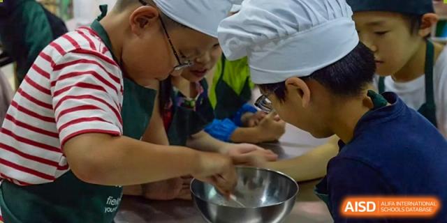 A Shanghai Livingston American School student participating in a cooking or culinary class, mixing ingredients in a bowl.