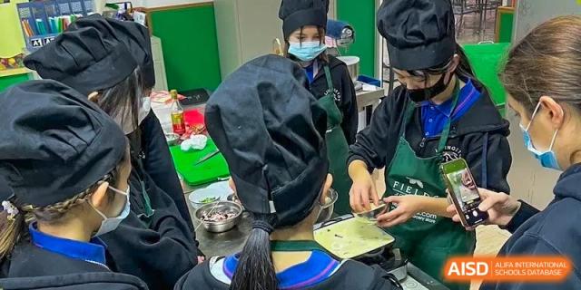 Shanghai Livingston American School students wearing chef hats and aprons, engaged in a hands-on cooking or nutrition lesson.