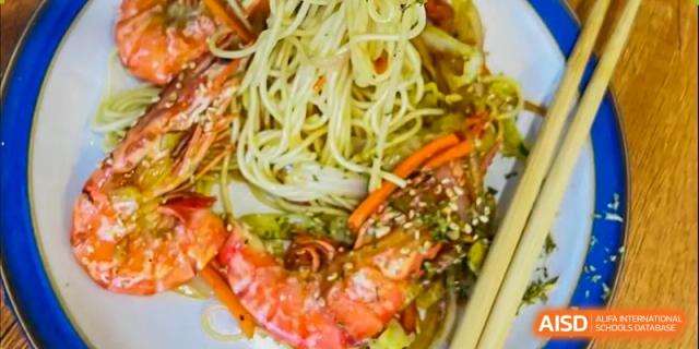 A close-up of a noodle dish with shrimp and other ingredients, showcasing a meal option at Shanghai Livingston American School.