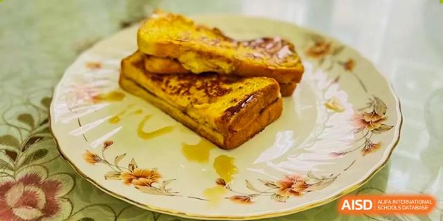 French toast drizzled with syrup on a decorative plate, suggesting a breakfast or dessert item at Shanghai Livingston American School.