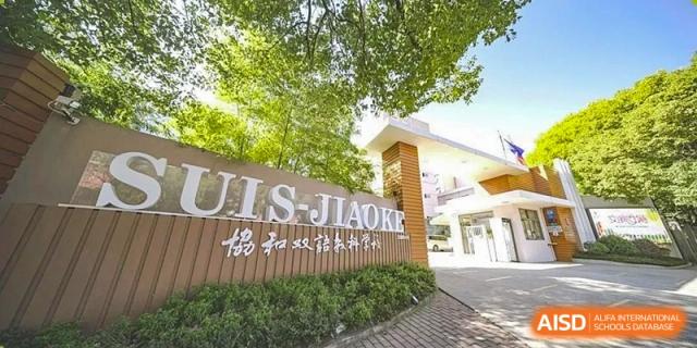 The main entrance sign for Shanghai United International School (SUIS-Jiaoke) Jiaoke Campus with Chinese characters and lush greenery surrounding it.