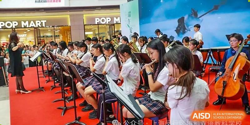 A group of students in uniform playing brass and woodwind instruments as an orchestra or band, possibly performing at an event at Shanghai United International School (SUIS-Jiaoke) Jiaoke Campus.