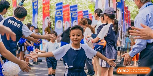 A smiling young male student in traditional attire posing outdoors at a school event or cultural festival at Western International School of Shanghai.