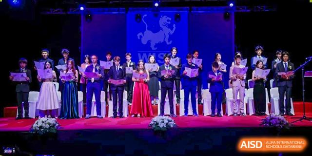 A group of older students and teachers in formal wear performing on a stage during a graduation or award ceremony at Western International School of Shanghai.