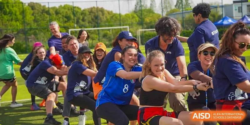 A team of students and adults participating in a fun outdoor tug-of-war competition during a field day event at Western International School of Shanghai.