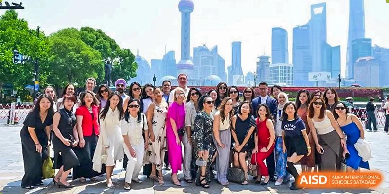 A large group of students and teachers posing for a photo outdoors with the Shanghai skyline in the background, likely on a school trip from Western International School of Shanghai.
