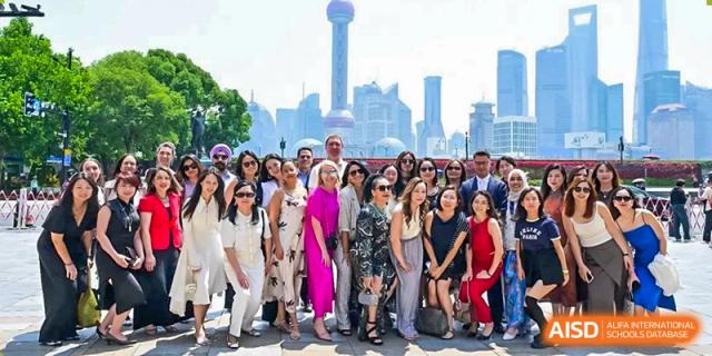 A large group of students and teachers posing for a photo outdoors with the Shanghai skyline in the background, likely on a school trip from Western International School of Shanghai.