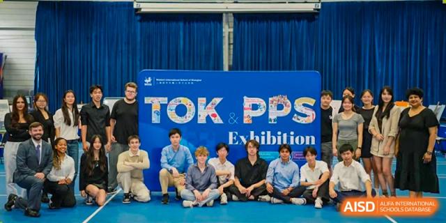 A group of high school students sitting in front of a colorful backdrop advertising the TOK, PPS, and Exhibition student work at Western International School of Shanghai.