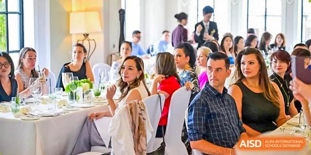 Adults, including teachers and parents, socializing and enjoying a formal meal at a school event at Western International School of Shanghai.