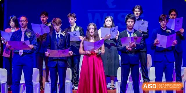 A group of students in formal wear singing or performing a musical number on a stage during an event at Western International School of Shanghai.