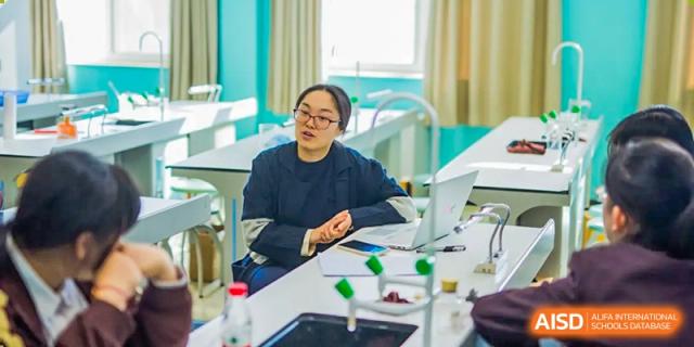 A female teacher sits alone, looking up while supervising an experiment setup in a science lab at Yinghua Academy of Tianjin.