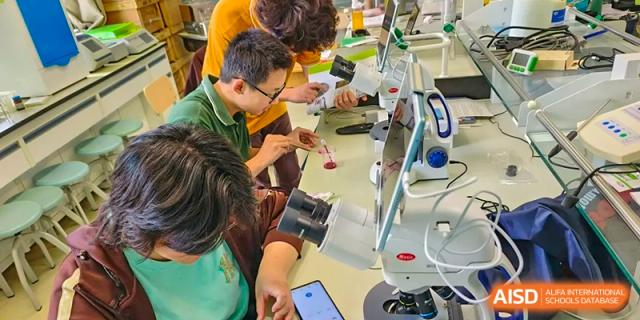 A group of students and an adult work closely together on a hands-on technical project involving wires and small devices at Yinghua Academy of Tianjin.