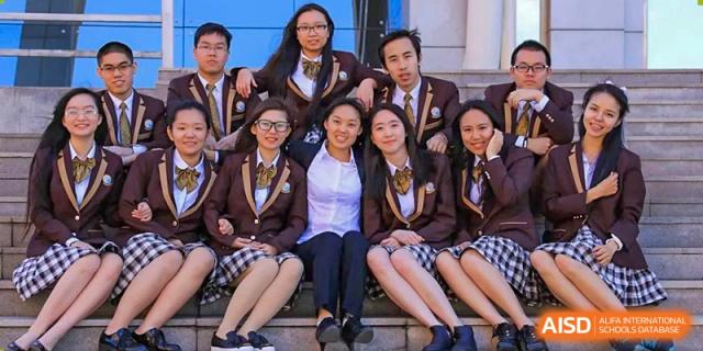 A group of male and female students sit together, smiling and posing casually for a photo at Yinghua Academy of Tianjin.
