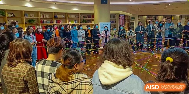 A crowd of people, many wearing masks, gathered for an indoor school event or activity at Yinghua Academy of Tianjin.