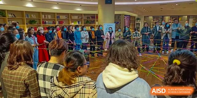 A crowd of people, many wearing masks, gathered for an indoor school event or activity at Yinghua Academy of Tianjin.