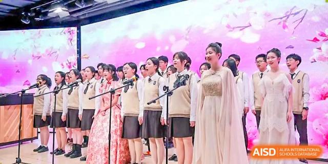 A group of female students in uniform singing together on stage during a choir performance at Yinghua Academy of Tianjin.