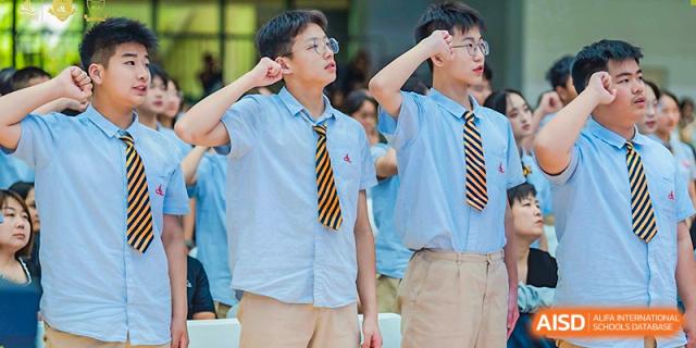 Two male students in uniform posing outdoors, looking up and shading their eyes, at Suzhou Science and Technology Town Foreign Language High School.