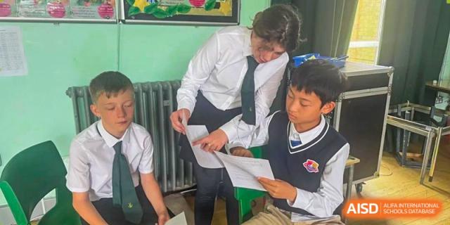 A teacher helps a young male student with schoolwork or a task in a classroom at Suzhou Science and Technology Town Foreign Language High School.