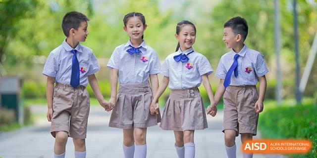 Two young female students in matching uniforms holding hands and smiling outdoors at Suzhou Science and Technology Town Foreign Language High School.