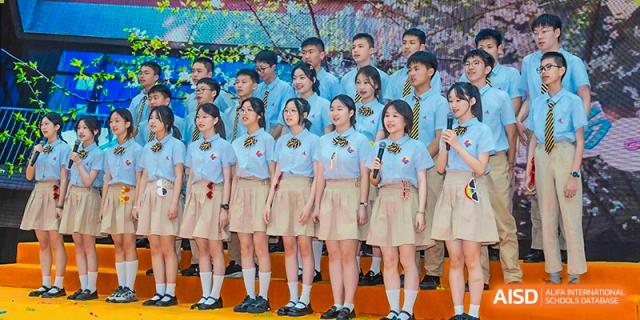 A group of female students in uniform standing and singing or performing on a stage at Suzhou Science and Technology Town Foreign Language High School.