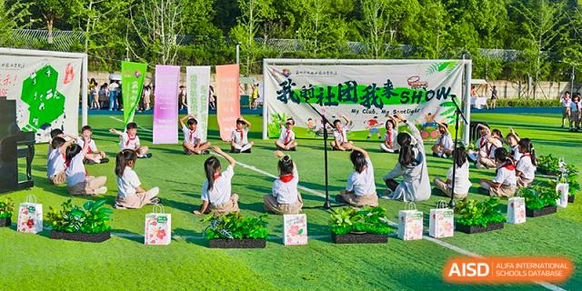 Young students seated on a green field participating in an outdoor performance or activity at Suzhou Science and Technology Town Foreign Language High School.