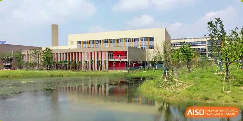 The modern school building exterior reflected in a body of water on the campus of Suzhou Science and Technology Town Foreign Language High School.