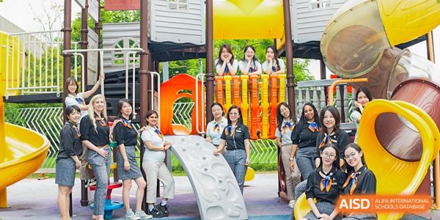 A group of students smiling while posing on or near colorful playground equipment at Suzhou Science and Technology Town Foreign Language High School.