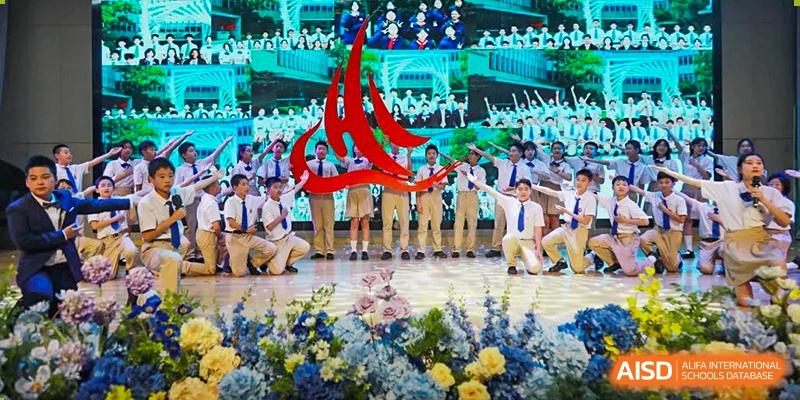 A large group of students in white and dark uniforms performing a coordinated dance on a stage with floral decorations at Suzhou Science and Technology Town Foreign Language High School.