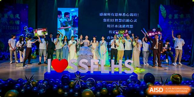 Students and staff on a brightly lit stage during an awards ceremony or event, with "SSTFLHS" displayed. Suzhou Science and Technology Town Foreign Language High School.